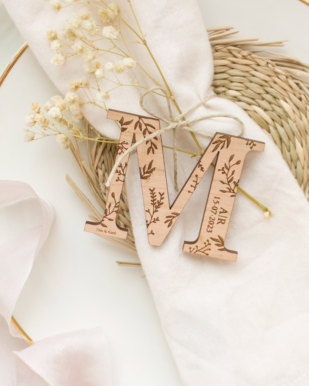 Letra M de madera sobre el plato de un invitado de boda