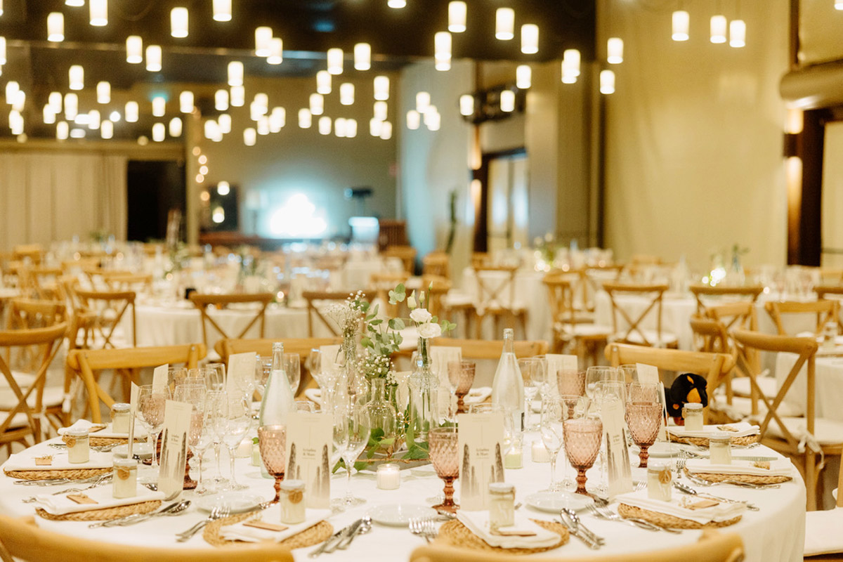 Comedor de la boda decorado con tonos verdes, luces cálidas y detalles personalizados para cada invitado.