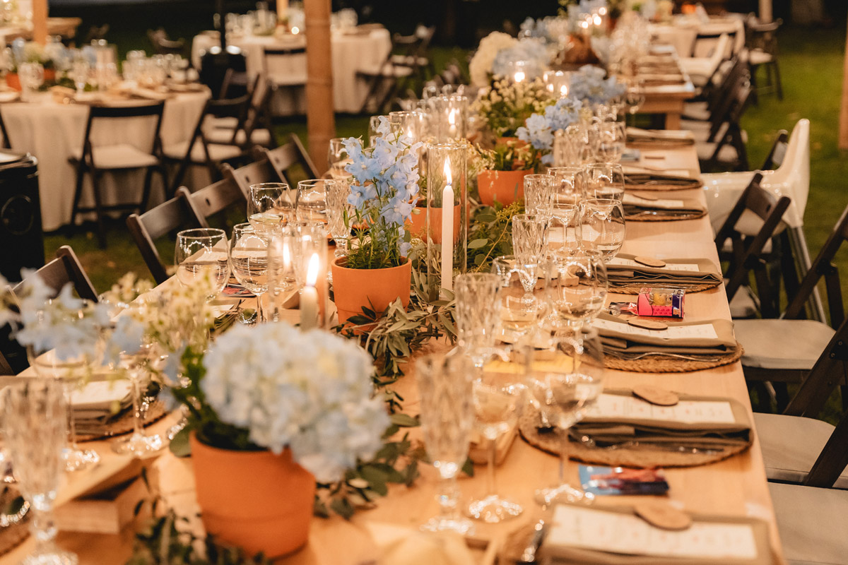 Decoración de mesas de boda con velas, margaritas y plantas aromáticas, creando un ambiente acogedor y natural