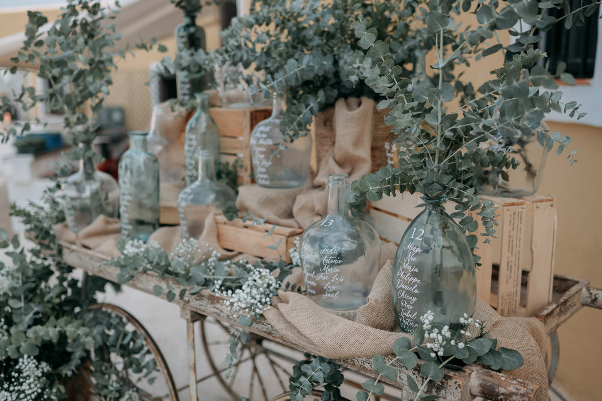 Carrito decorado para seating plan de boda con botellas vintage