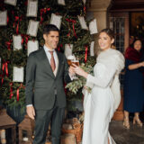 Seating plan de boda sobre abeto con cintas de terciopelo rojo y etiquetas colgantes
