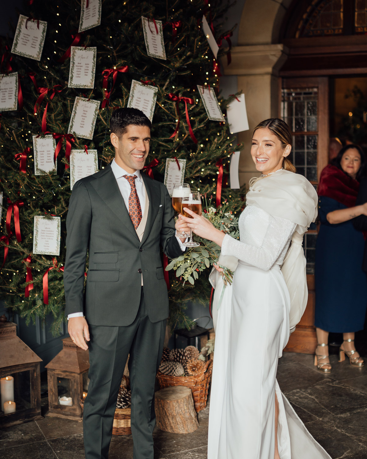 Seating plan de boda sobre abeto con cintas de terciopelo rojo y etiquetas colgantes